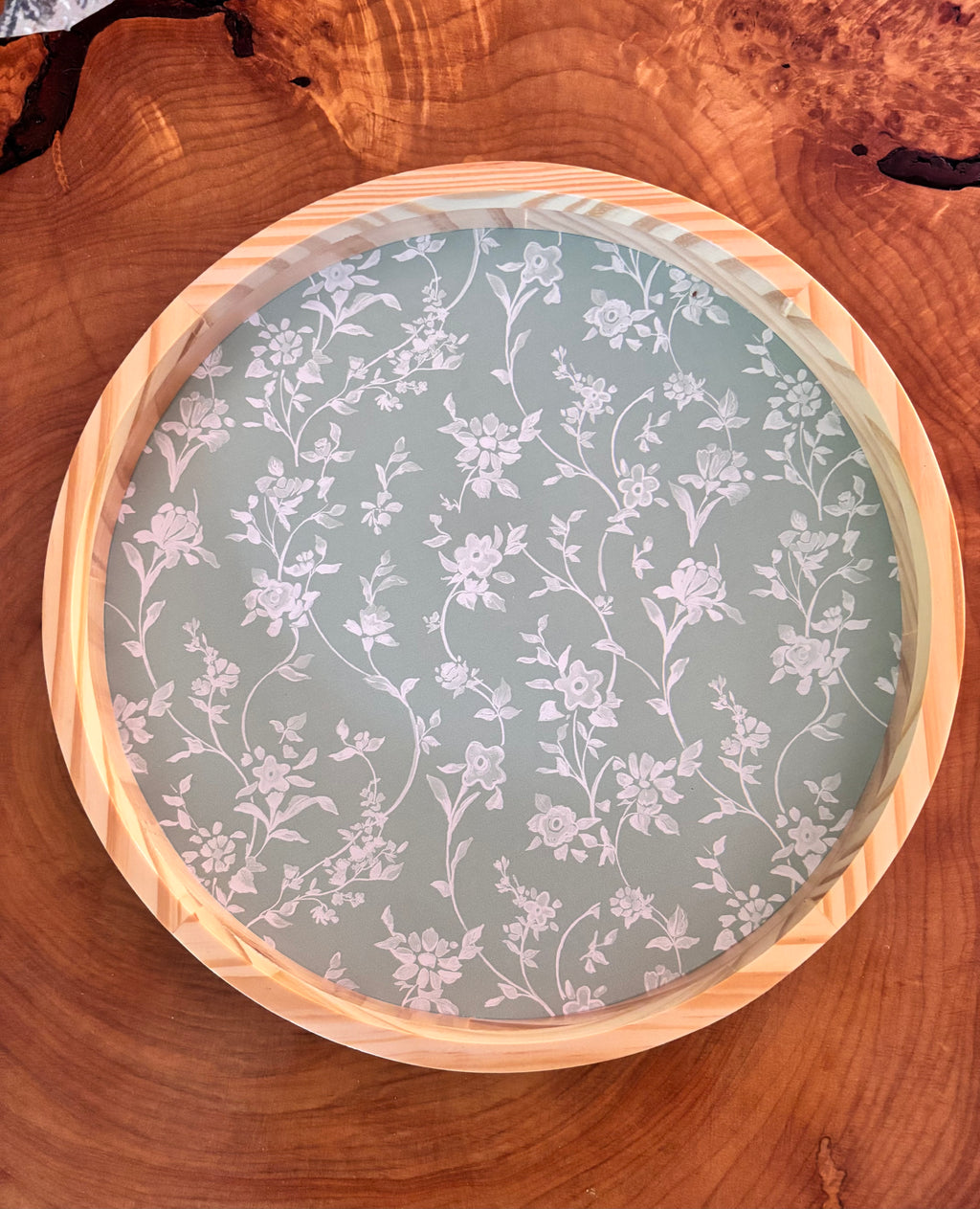 Round wooden tray with floral patterned insert on a wooden surface