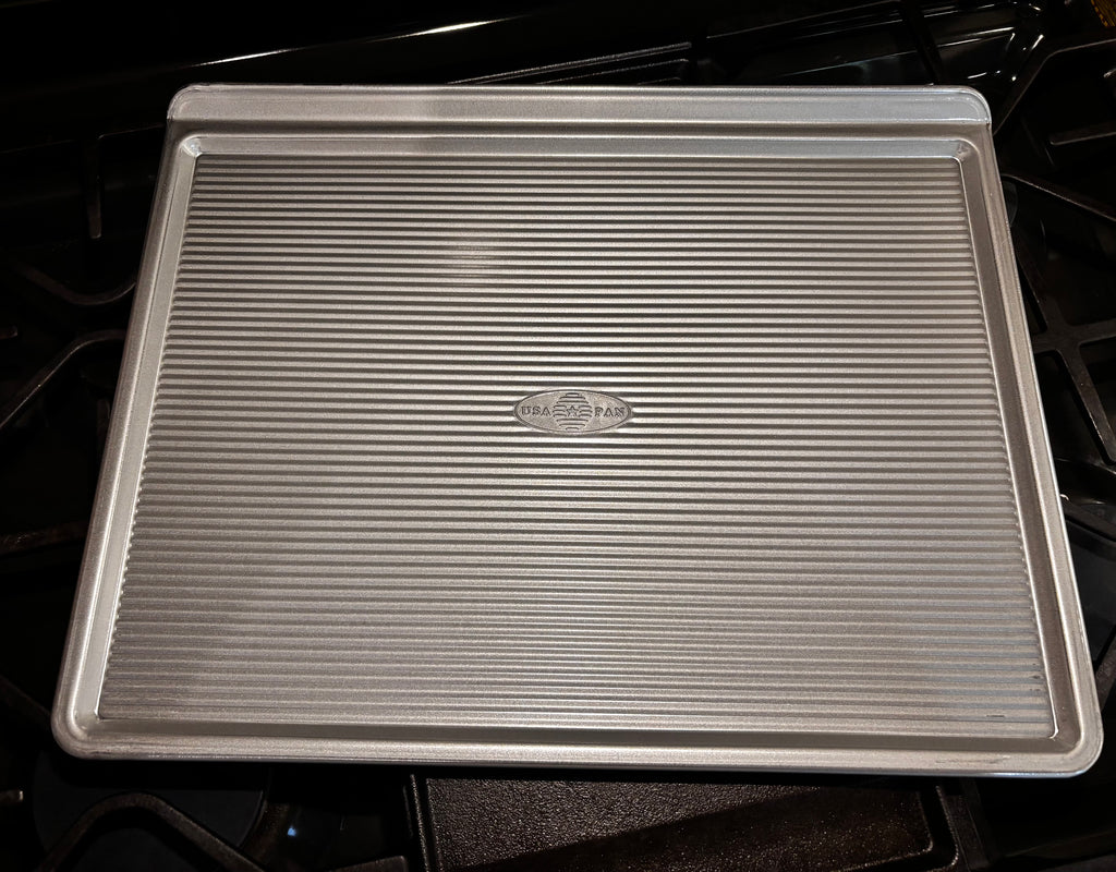 Top view of the USA Pan large cookie sheet with embossed logo and raised gripping edge.