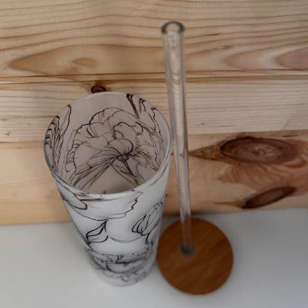 op-down view into the floral glass tumbler, with the bamboo lid and clear glass straw beside it.