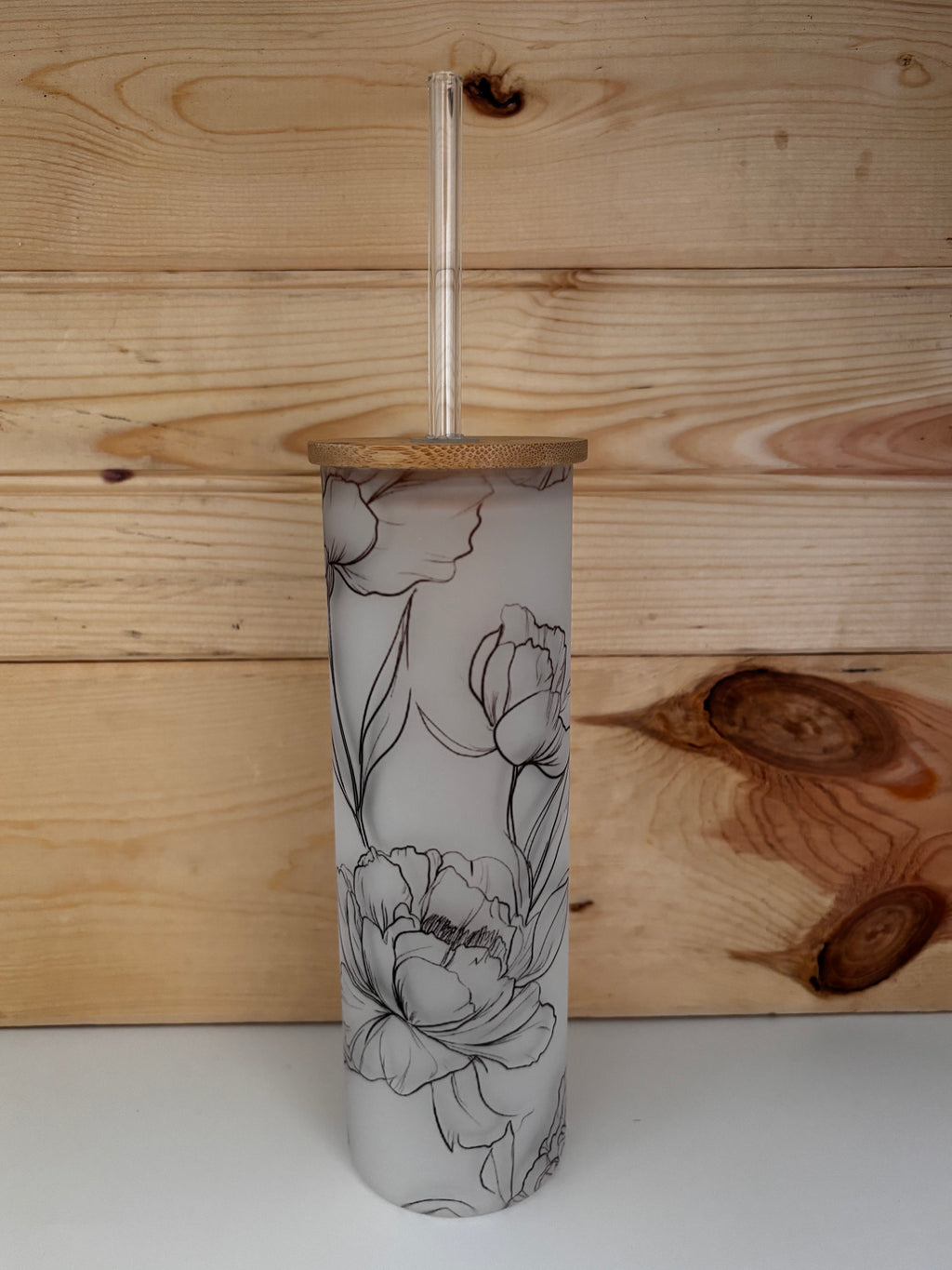 Front view of the frosted peony glass tumbler with bamboo lid and uncovered clear glass straw.